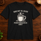Decaf is Just Performance Art T-Shirt in Black, close-up on dark wood coffee bar