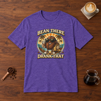 Bean There Drank That T-Shirt Heather Purple flat lay on walnut coffee bar